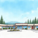 A modest rural hospital campus surrounded by pine trees under a clear sky